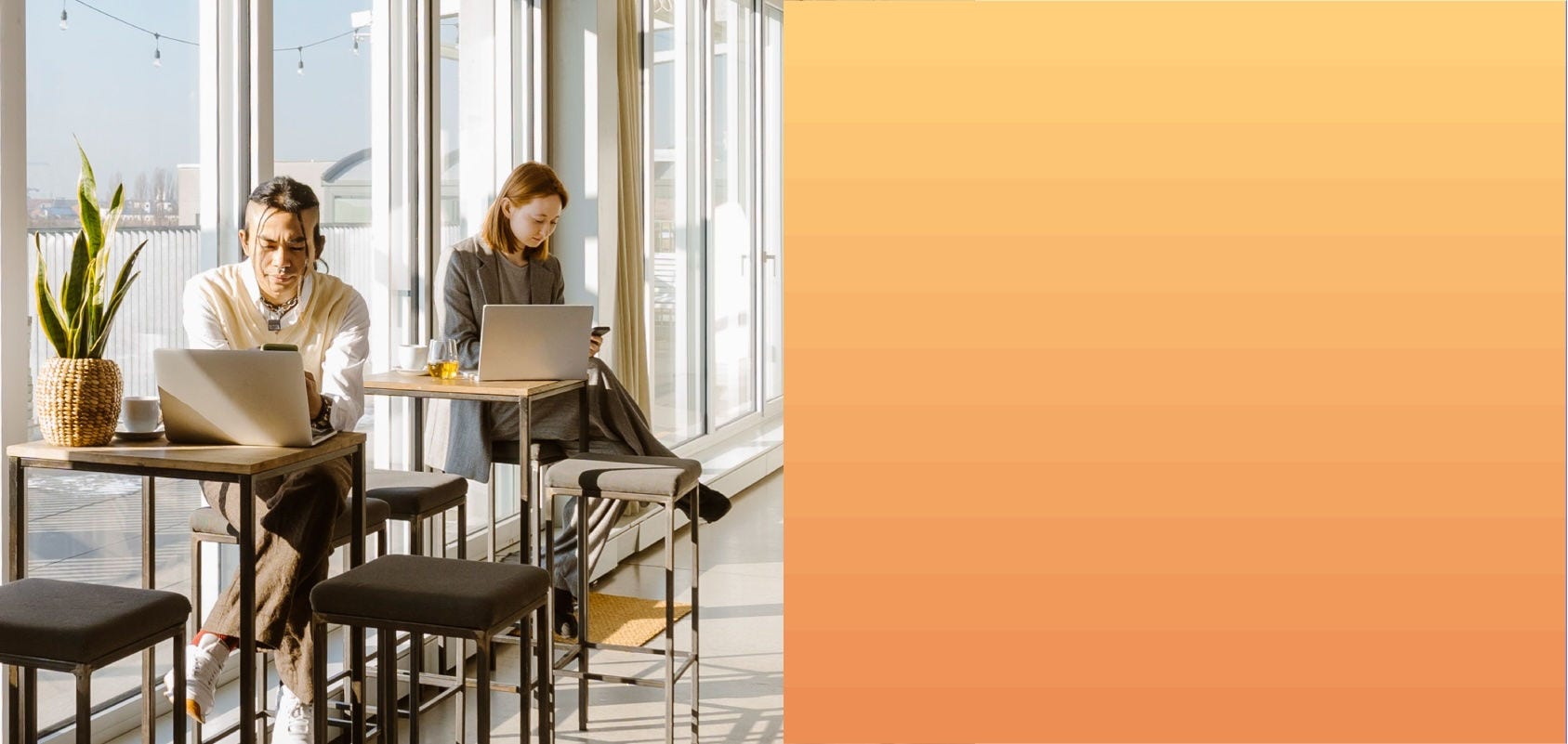 Man and woman use their cell phones in front of their open laptops at a cafe.